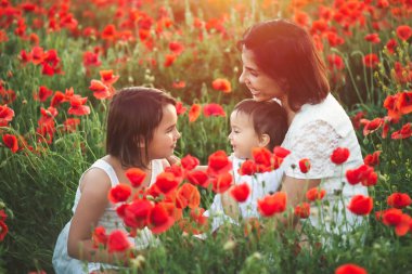 Anne ve kızları gelincik tarlasında günbatımının tadını çıkarıyorlar. Anneler günü konsepti