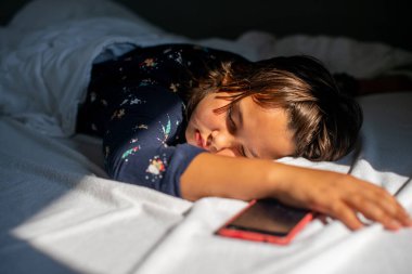 The girl sleeping with her phone in bed due to her addiction to it.