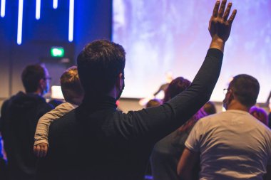 Kilise ayininde Tanrı 'ya şükreden insanların elleri havada.