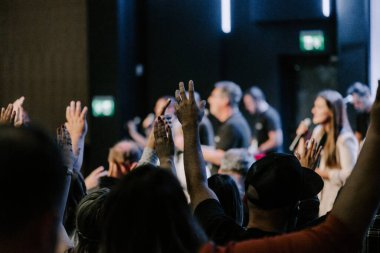 Kilise ayininde Tanrı 'ya şükreden insanların elleri havada.