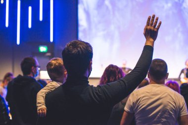 Kilise ayininde Tanrı 'ya şükreden insanların elleri havada.