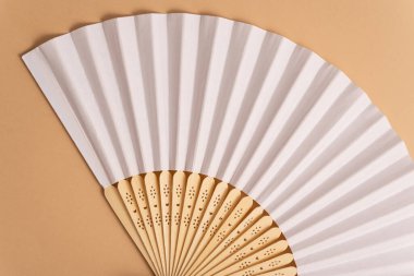 Geleneksel beyaz el yelpazesini yaz modeli için katlıyorum. Bej arkaplan