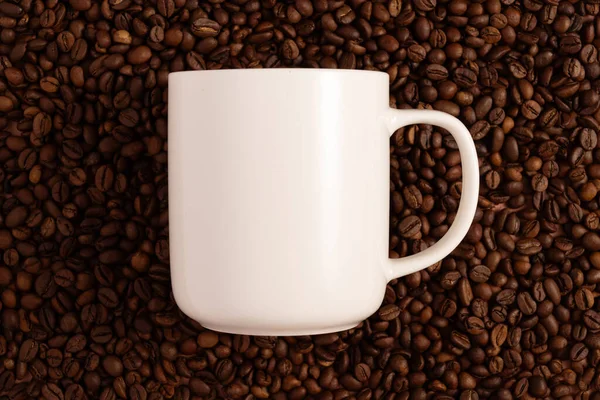 Blank white mug mock-up on brown background with coffee beans