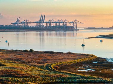 Gün batımında nehirde nakliye vinçleri