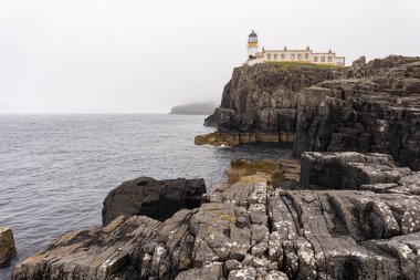 Photo of the Neist Point lighthouse on top of the rocky cliff during a summer day in the Highlands, Scotland