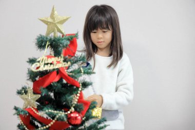 Japanese student girl decorating Christmas tree (8 years old)