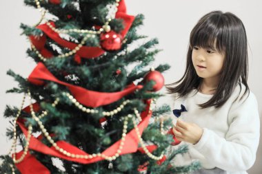 Japanese student girl decorating Christmas tree (8 years old)