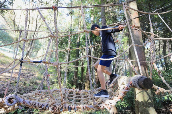 Japanese junior high school student playing at outdoor obstacle course (13 years old)