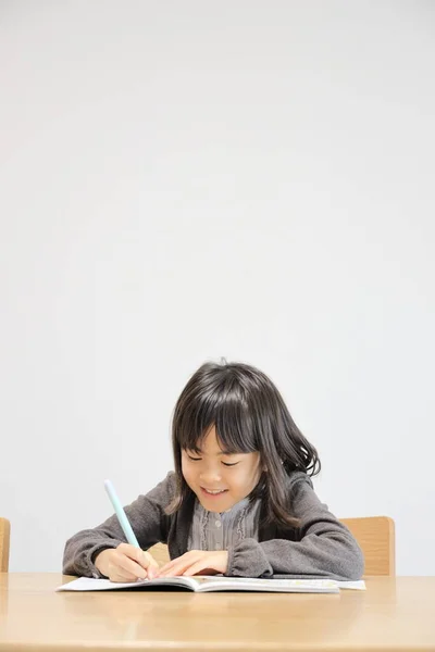 Japanese student girl studying in dining room (8 years old)