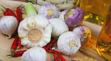 Yalıtılmış tek başına sarımsak ve zeytin odunu kesme tahtası, biber ve yağ şişeleri üzerinde taze ampul.