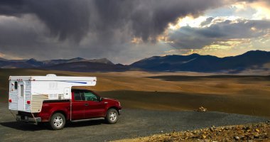 4x4 Kamper kamyonu, platoda, sonsuz kurak İzlanda manzarası, karanlık strom bulutlarıyla hava değişimi - merkezi İzlanda