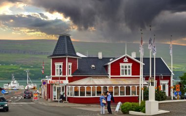 Akureyri (Bautinn restaurant), Iceland - July 9. 2008: Traditional icelandic red wood building, weather change with dark storm clouds announcing upcoming thunderstorm