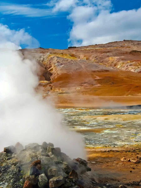 Steaming hot fumarole on geothermal field, yellow deposits of sulfates, red volcanic mountains, blue summer sky - Seltun  Krysuvik Iceland