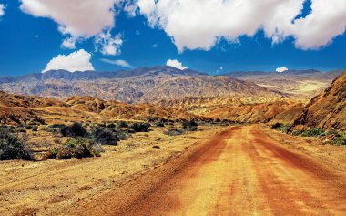 Beautiful red desert landscape, empty dirt road track into valley, arid rugged hills and mountains - Chile, Atacama region, Pan de Azucar NP