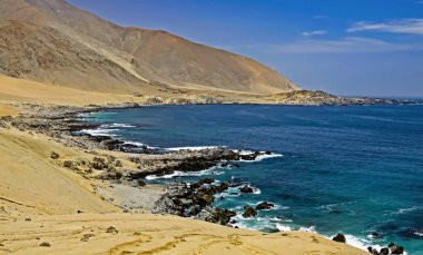 Kuru kumlu atacama çöl dağları ıssız körfezde mavi Pasifik okyanusuyla buluşur.