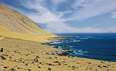 Atacama Çölü ıssız, vahşi okyanus kayalık kıyılarıyla karşılaşır: kuru kumlu dağlar, ıssız körfez, mavi deniz - Pan de Azucar, Kuzey Şili