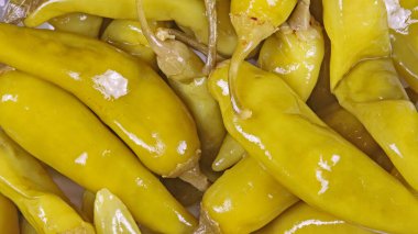 Pek çok sarı yeşil turşulu çiğ pepperoninin tam kare görüntüsü.