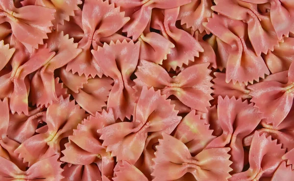 stock image Full frame closeup of many bow tie butterfly shape uncooked raw pink italian farfalle pasta noodles as background