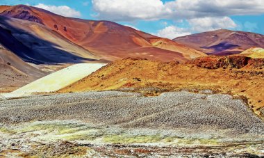 Issız, boş, kumlu toprak bir yolda, bitkisiz, kırmızı turuncu renkli dağları olan vahşi bir çöl arazisinde Cordillera Copiapo, Atacama, Şili