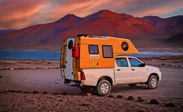 One 4x4 camper truck on lonely camp site at high lake plateau in andes mountains, evening sunset, red mountains -  Laguna Miscanti, Chile