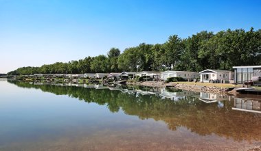 Hollanda, Arcen, Limburg, Hollanda 'daki Hollanda tatil parkındaki sakin göl kıyısındaki güzel tatil evleri.