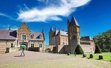 Mavi yaz gökyüzüne karşı ortaçağ kale girişine giden köprü yolu Kasteel Heeswijk, Hollanda