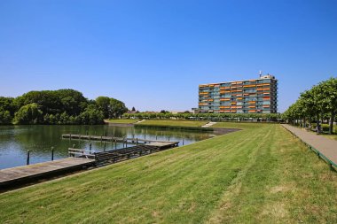 Şehrin varoşlarında güzel bir yüzme gölü manzarası, jettie, yeşil çayır, göl kenarındaki apartman dairesi, bisiklet yolu - Oosterplas den Bosch, S-Hertogenbosch