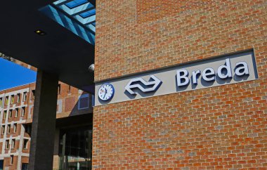 Breda, Hollanda - 30 Ağustos. 2023: Üzerinde Hollanda tren istasyonu ve saatinin logosu olan kırmızı tuğla duvar