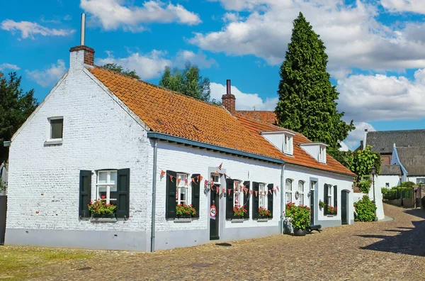 Thorn (Limburg), 30 Ağustos. 2023: Cobblestone Caddesi, kırsal kesimde kırmızı çatılı geleneksel beyaz Hollanda evi