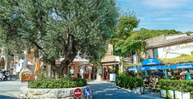 Ramatuelle, Fransa - 9 Haziran. 2016: Yaz aylarında tipik bir Fransız kafe restoranına sahip, huzurlu bir Akdeniz köyünde büyük bir zeytin ağacının olduğu güzel bir meydan