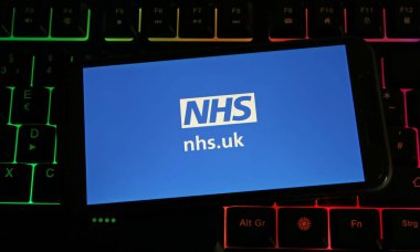 Viersen, Almanya - 9 Temmuz. 2023: Cep telefonunun bilgisayar klavyesinde NHS.uk ulusal sağlık servisi logosu ile kapatılması