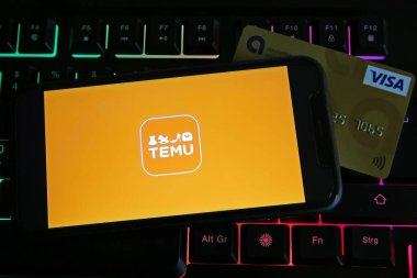 Viersen, Almanya - 9 Temmuz. 2023: Cep telefonunun bilgisayar klavyesinde Temu çevrimiçi pazarının logosu ve kredi kartıyla kapatılması