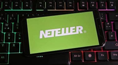 Viersen, Almanya - 9 Ocak. 2024: Neteller 'in logosu ile birlikte bilgisayar klavyesindeki akıllı telefonun kapatılması