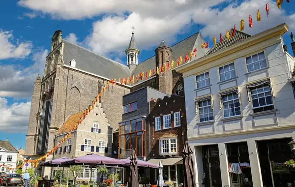 stock image Grave, Netherlands (Noord-Brabant) - July 9. 2024: Market square with cafes, restaurants and church in historical dutch town center (focus on center)