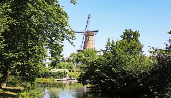 stock image Beautiful idyllic river water landscape with traditional dutch windmill in rural old countryside town - Ravenstein, Netherlands, Noord-Brabant