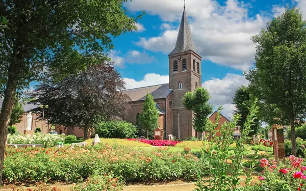 stock image Kinrooi (Geistingen, Sint-Lambertuskerk), Belgium - July 9. 2024: Beautiful medieval church with blooming summer garden in belgian village