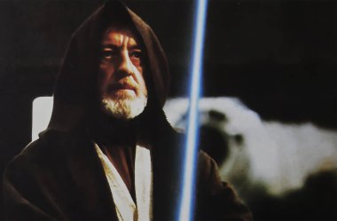 Viersen, Germany - July 9. 2024: Star Wars cinema film lobby card detail with Alec Guinness as Obi-Wan Kenobi with laser sword from 1977 (focus on person) clipart