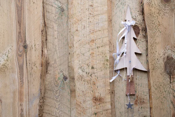 Background of rustic timber slats that are side by side. A small decorative wooden Christmas tree was attached to it.