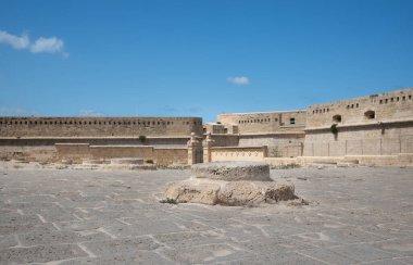 Fort St. Elmo, Malta 'nın önündeki meydanda bulunan küçük bir taş sütunun ayrıntıları. Yuvarlak taşlardan yapılmış birçok açıklık kapalı ve meydanda görülebilir. Arka planda duvar var..