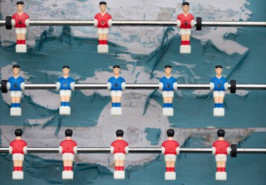Sopaların üzerinde figürler olan eski bir plastik futbol maçı. Rakamlar eski ve yırtık pırtık futbol sahasının üzerinde kukla gibi asılı duruyor. Oyunda iki takım var..