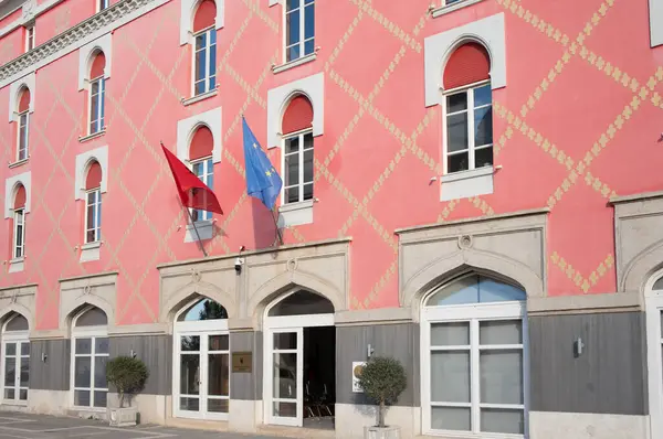 Arnavutluk 'un Tiran kentinde, şehrin ortasında pembe bir ev. Bakanlığın kapısında Arnavut ve Avrupa bayrağı var.