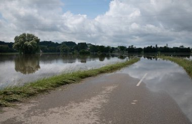Almanya 'da bir yol sular altında. Arka plandaki ağaçlarda ve gökyüzünde birçok bulut var. Her yerde su var...