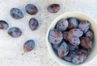 Beyaz bir seramik kasede duran mavi eriklerin yakın çekimi. Bir eriğin kalp şekli vardır. Arka planda, diğer meyvelerle birlikte hafif bir arkaplan.