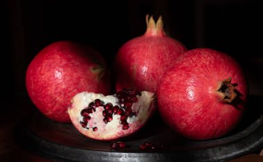 Eski metal bir tepside duran olgun kırmızı narı yakından çek. Bir nar kesilir..