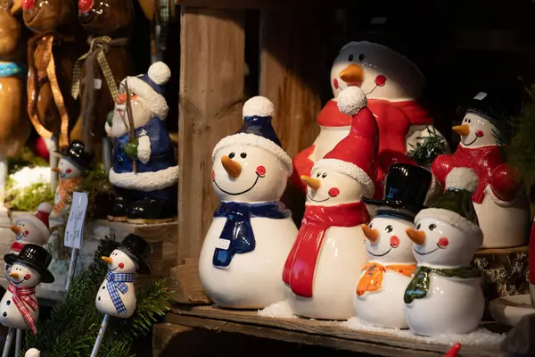 Küçük seramik kardan adamlar Noel pazarında satılıktır. Figürlerin komik yüzleri var..