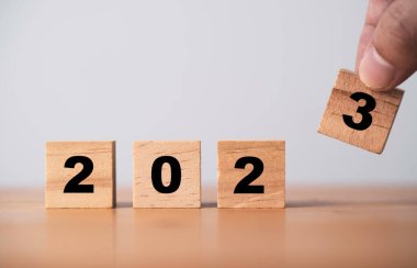 Yeni yıl değişimine hazırlık için ahşap blok küpü üzerinde 2023 'ü elle birleştirin ve yeni iş hedefi stratejisi kavramına başlayın.