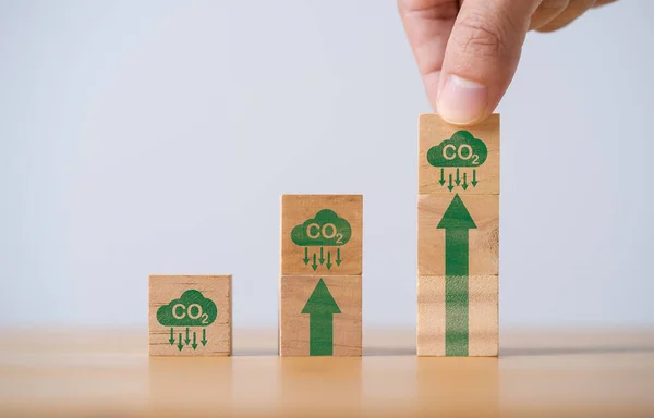 Hand stacking CO2 reducing icon with up arrow for decrease CO2 , carbon footprint and carbon credit to limit global warming from climate change, Bio Circular Green Economy concept.