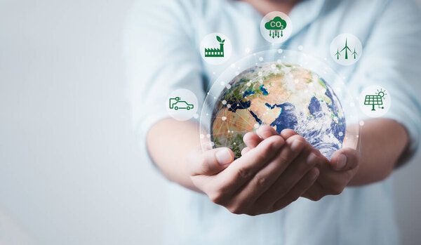 Бизнесмен удерживает мир с иконкой сокращения СО2 для уменьшения СО2, углеродного следа и углеродного кредита, чтобы ограничить глобальное потепление от изменения климата, концепция Био циркуляр зеленой экономики. Элемент изображения НАСА