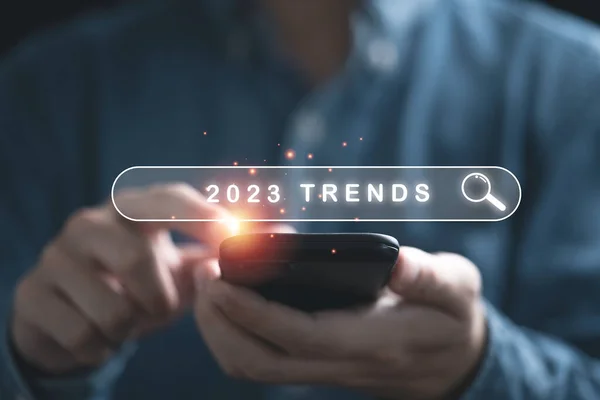 İş adamı akıllı telefonu elinde tutuyor ve pazarlama izleme ve iş planlama değişikliği kavramı için 2023 trend yılına sahip arama barına sahip..