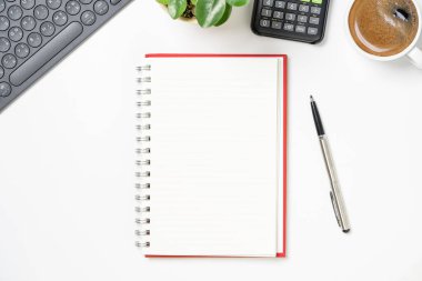 Top view of blank notebook with pen coffee calculator and computer keyboard for office working desk concept.